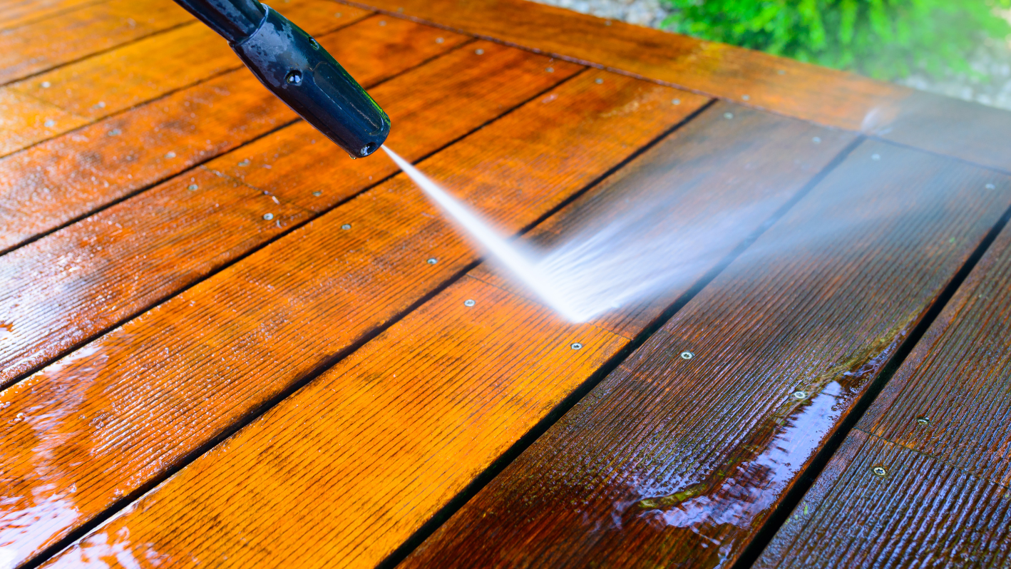 A person spraying water on a wooden deck